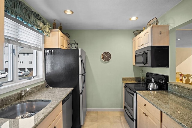 kitchen featuring stone counters, light brown cabinets, stainless steel appliances, and a sink