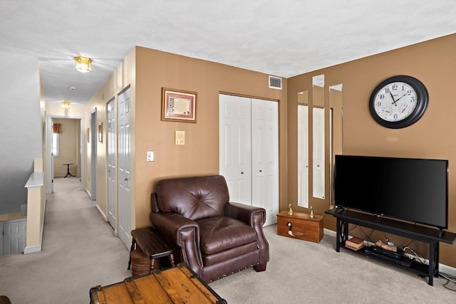 living area with baseboards, visible vents, and light colored carpet