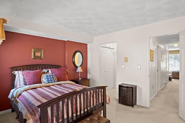 bedroom featuring light carpet, baseboards, and a closet