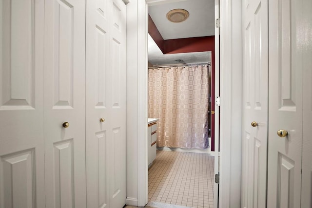 full bath with curtained shower, a closet, and tile patterned flooring