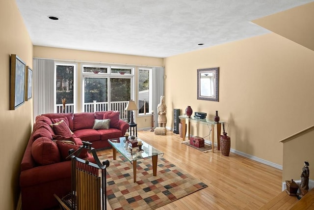 living room with a textured ceiling, baseboards, and wood finished floors