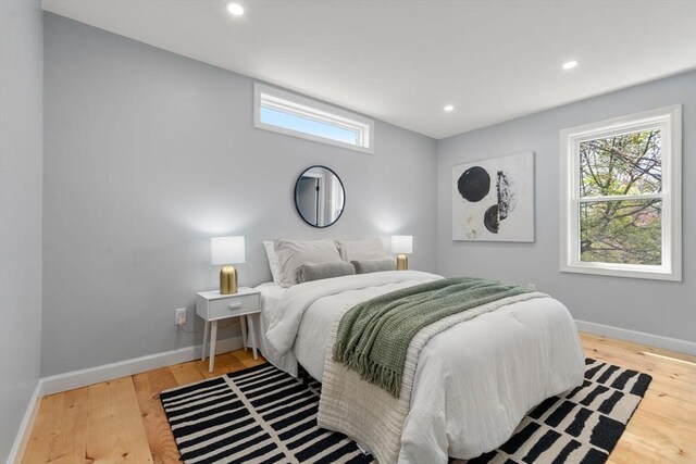 bedroom with baseboards, multiple windows, and wood finished floors