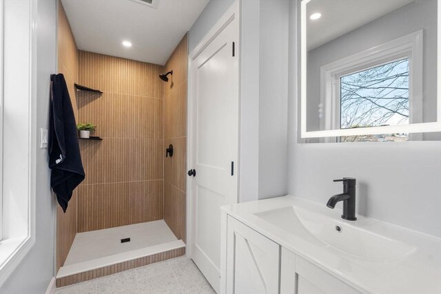 full bath with vanity, baseboards, a tile shower, and recessed lighting