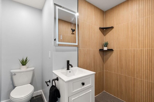 bathroom featuring vanity, baseboards, tile patterned flooring, and toilet