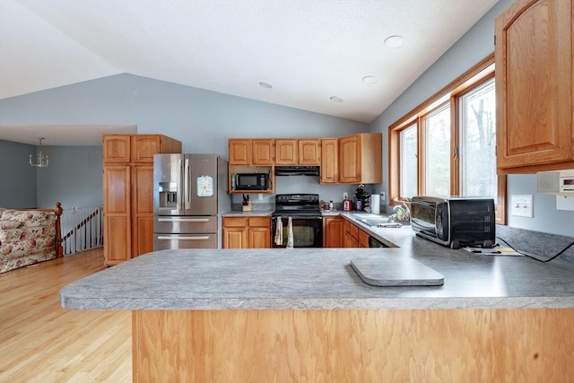 kitchen featuring kitchen peninsula, vaulted ceiling, sink, black appliances, and light hardwood / wood-style flooring