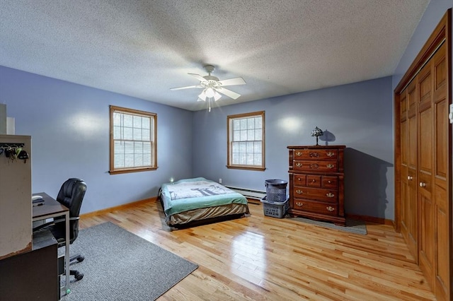 bedroom featuring ceiling fan, a baseboard radiator, a textured ceiling, a closet, and light wood-type flooring