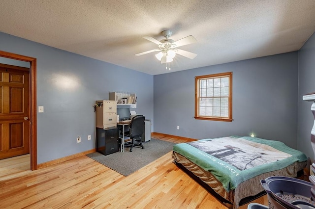 bedroom featuring ceiling fan, light wood-type flooring, and a textured ceiling