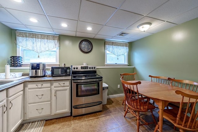 kitchen with white cabinets, a paneled ceiling, and stainless steel range with electric cooktop