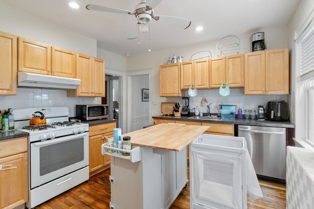 kitchen with a center island, stainless steel appliances, light brown cabinetry, and dark hardwood / wood-style flooring