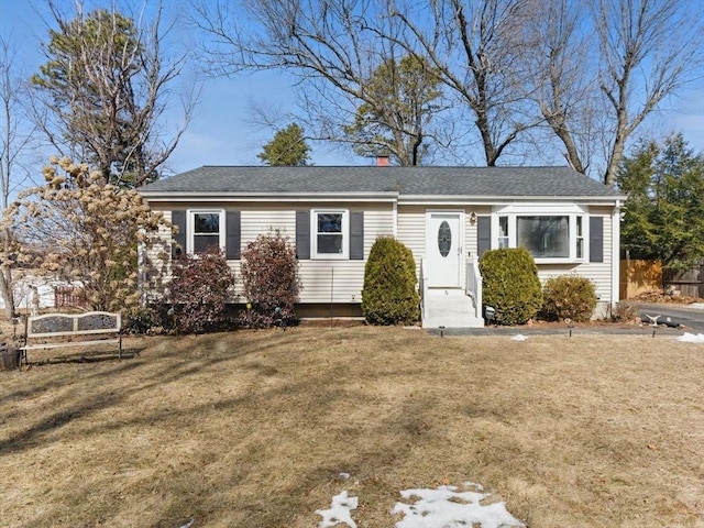 view of front of home featuring a chimney, fence, and a front lawn