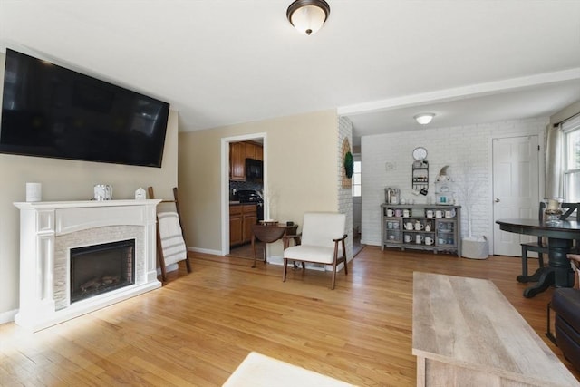 living area with light wood-type flooring, brick wall, and a fireplace