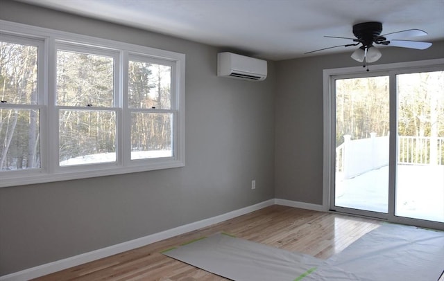 unfurnished room featuring baseboards, wood finished floors, and a wall mounted AC