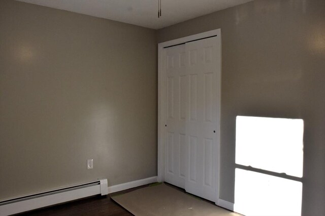 unfurnished bedroom with a baseboard radiator, a closet, and baseboards