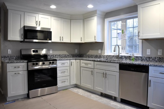 kitchen with appliances with stainless steel finishes, stone countertops, a sink, and white cabinetry