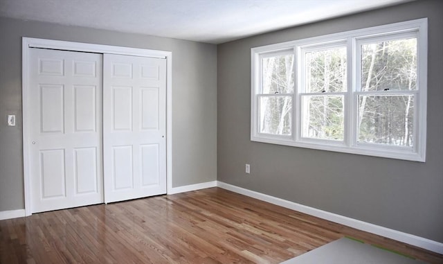 unfurnished bedroom with a closet, baseboards, and wood finished floors