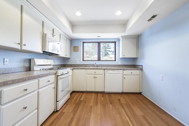 kitchen with white cabinetry, white appliances, light hardwood / wood-style floors, and a raised ceiling