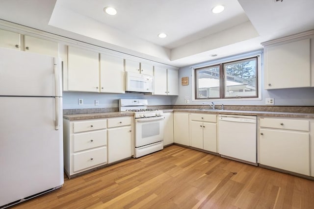 kitchen featuring white cabinetry, white appliances, and a raised ceiling