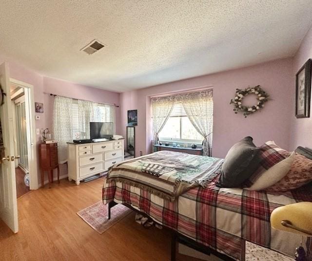 bedroom featuring light hardwood / wood-style floors and a textured ceiling