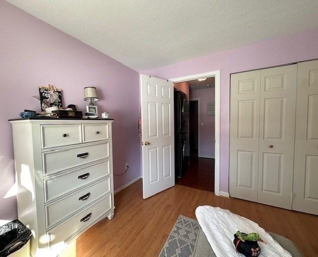 bedroom with light hardwood / wood-style flooring, a textured ceiling, and a closet