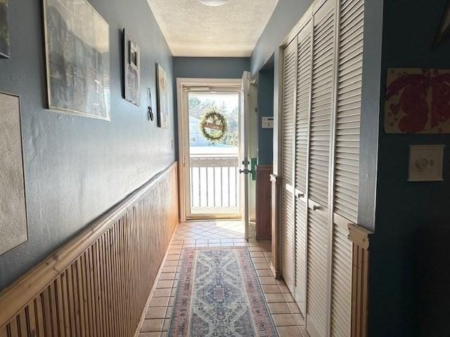 corridor with a textured ceiling and light tile patterned flooring