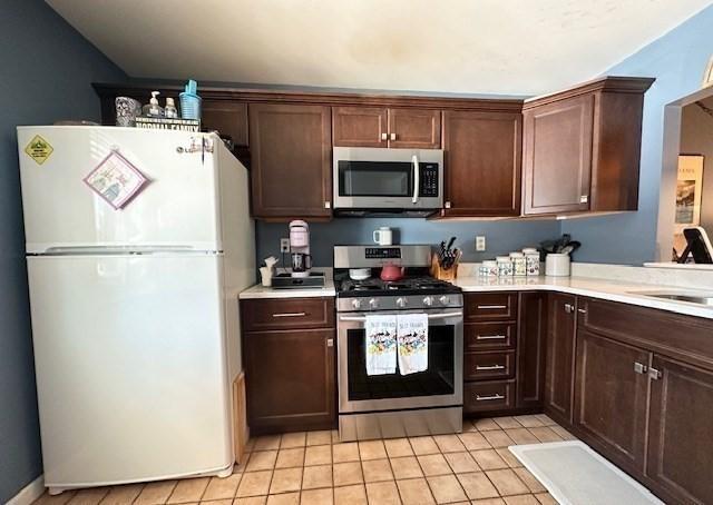 kitchen featuring dark brown cabinetry, stainless steel appliances, sink, and light tile patterned floors