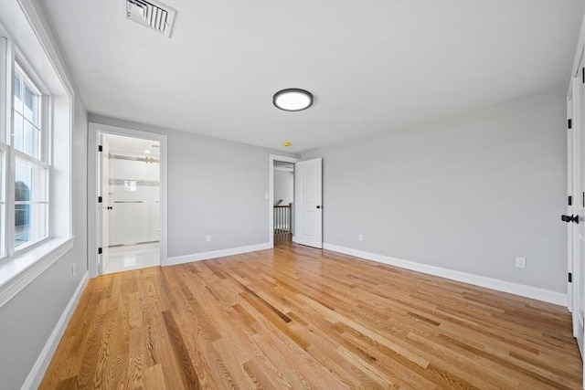 unfurnished bedroom with light hardwood / wood-style floors and ensuite bath