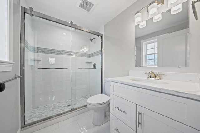 bathroom featuring tile patterned floors, vanity, toilet, and a shower with shower door