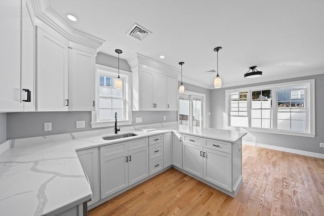 kitchen featuring kitchen peninsula, sink, white cabinets, light hardwood / wood-style floors, and hanging light fixtures