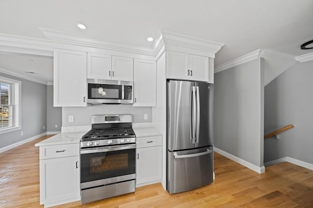 kitchen with white cabinetry, stainless steel appliances, and ornamental molding