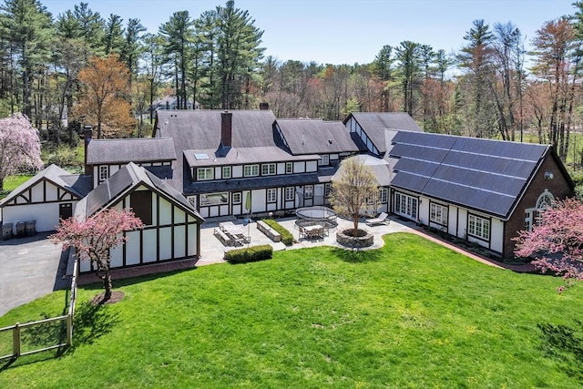 12 Old Meadow Rd, Dover, MA 02030 - back of property with solar panels, a yard, a chimney, and a patio area