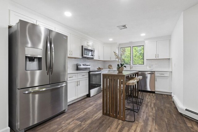 24 Roosevelt St, Taunton, MA 02780 - kitchen with stainless steel appliances, white cabinetry, dark wood-type flooring, backsplash, and light countertops