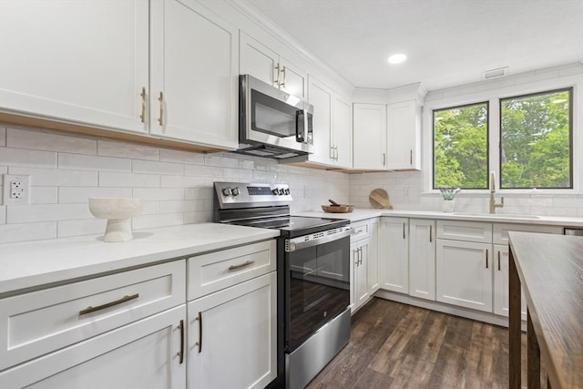 24 Roosevelt St, Taunton, MA 02780 - kitchen featuring appliances with stainless steel finishes, a sink, dark wood finished floors, white cabinets, and tasteful backsplash