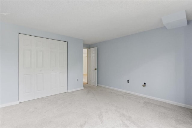 30 Revere Beach Pkwy Unit 207, Medford, MA 02155 - unfurnished bedroom with light colored carpet, a closet, baseboards, and a textured ceiling