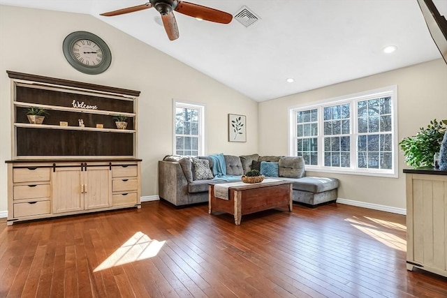 living area featuring baseboards, visible vents, a ceiling fan, dark wood-style flooring, and vaulted ceiling