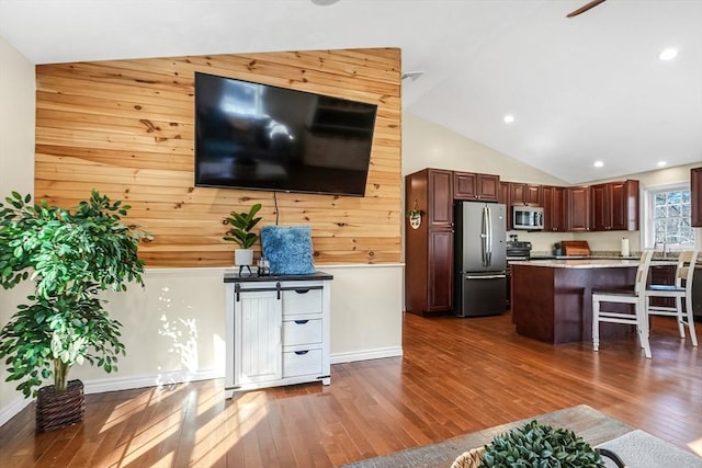 kitchen featuring baseboards, dark wood finished floors, appliances with stainless steel finishes, a kitchen breakfast bar, and light countertops