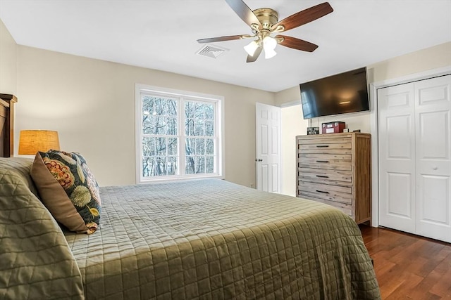 bedroom featuring dark wood-style floors, ceiling fan, visible vents, and a closet