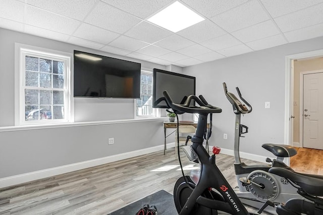 exercise area featuring a drop ceiling, wood finished floors, and baseboards