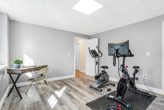 workout area with a drop ceiling, wood finished floors, and baseboards