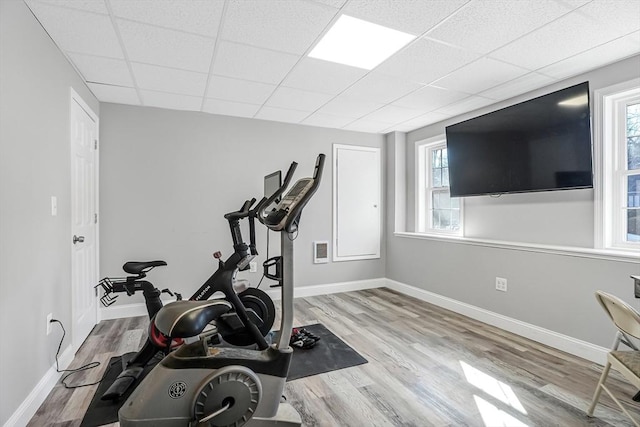 workout room with baseboards, a drop ceiling, and wood finished floors