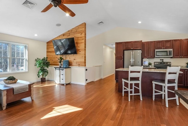 kitchen with visible vents, appliances with stainless steel finishes, a breakfast bar, and wood finished floors