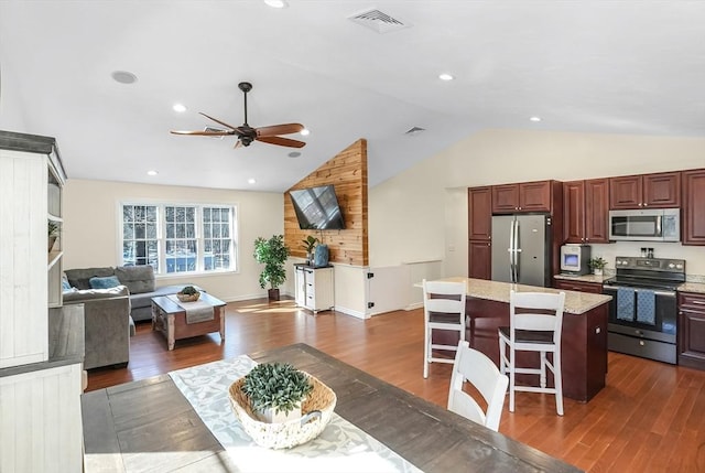 interior space featuring dark wood-style floors, a breakfast bar, stainless steel appliances, visible vents, and a kitchen island