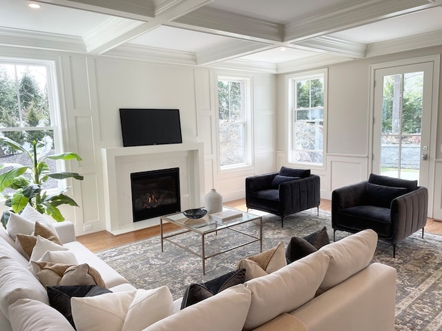 living room featuring light wood-type flooring, ornamental molding, and coffered ceiling