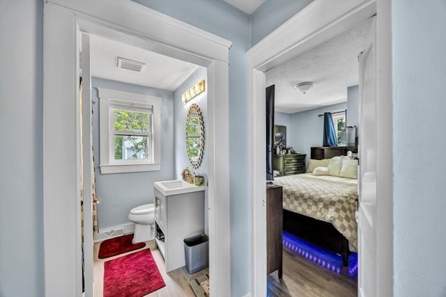 60 Grove St, Barnstable, MA 02601 - ensuite bathroom featuring wood finished floors, toilet, baseboards, and a sink