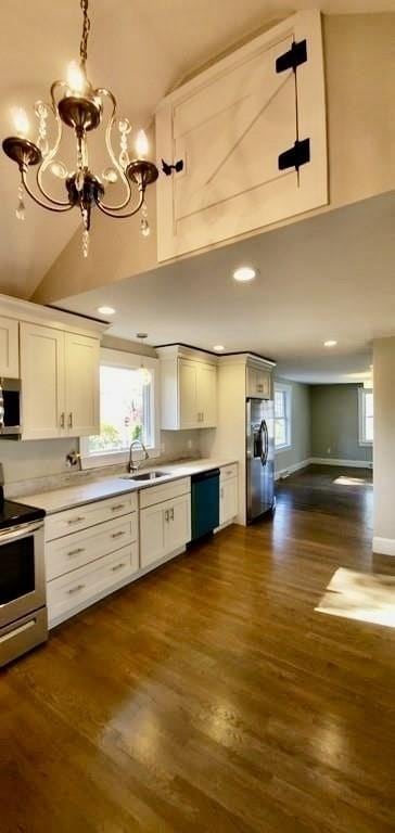 60 Grove St, Barnstable, MA 02601 - kitchen with stainless steel appliances, a chandelier, white cabinetry, dark wood-style flooring, and high vaulted ceiling