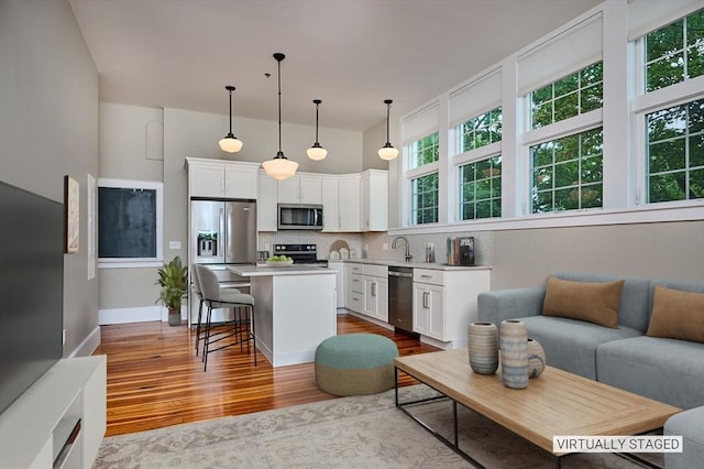 58 Main St Unit 4, Hatfield, MA 01038 - kitchen featuring appliances with stainless steel finishes, wood finished floors, white cabinets, and decorative backsplash
