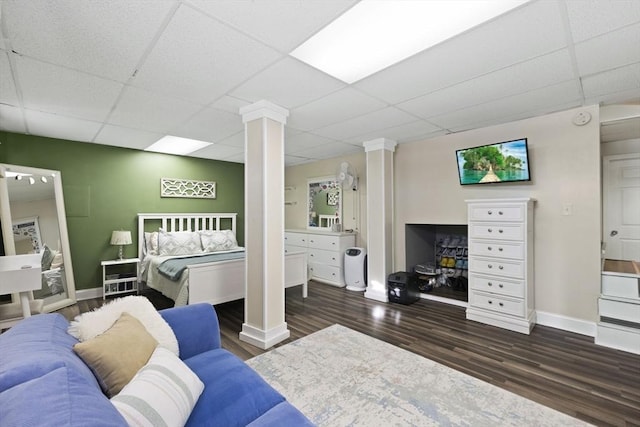 bedroom featuring decorative columns, a drop ceiling, and dark hardwood / wood-style floors