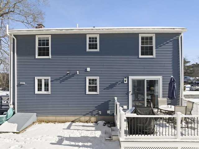 snow covered back of property featuring a wooden deck