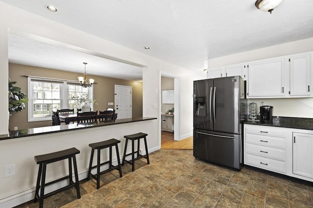 kitchen featuring baseboard heating, white cabinets, stainless steel refrigerator with ice dispenser, an inviting chandelier, and hanging light fixtures