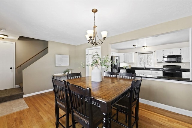 dining area featuring sink, light wood-type flooring, and a chandelier