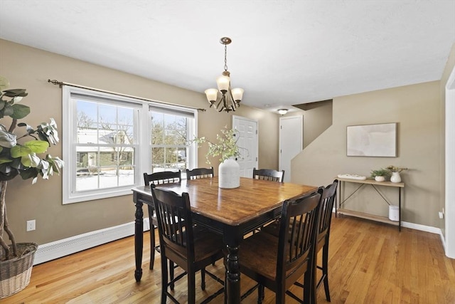 dining space with light hardwood / wood-style floors, an inviting chandelier, and a baseboard radiator